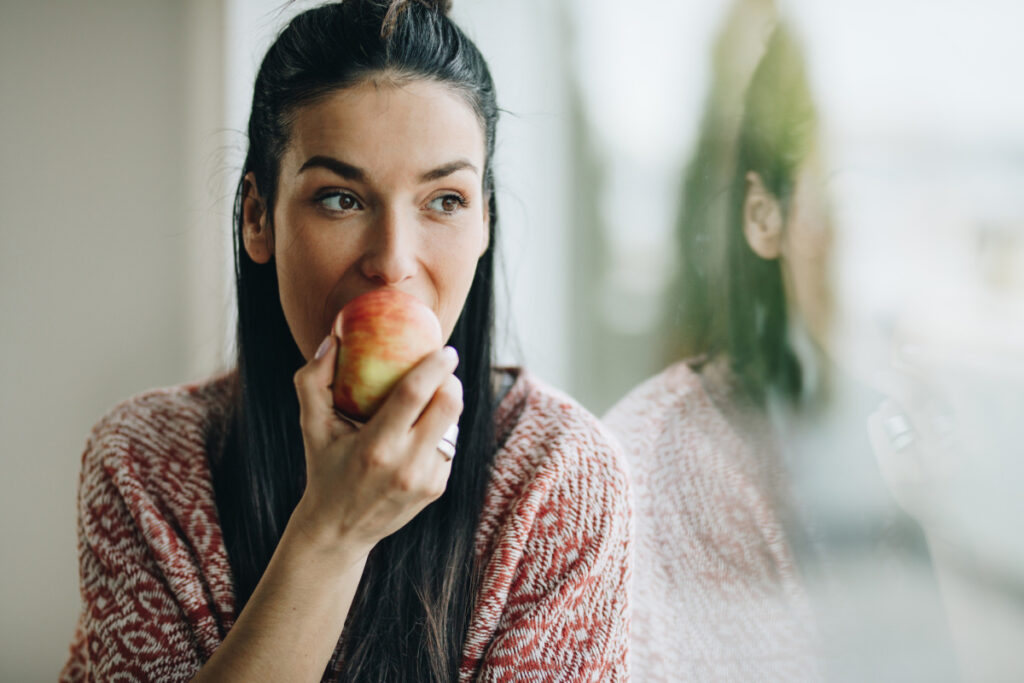 Young woman eating a fresh apple as part of a FODMAP diet