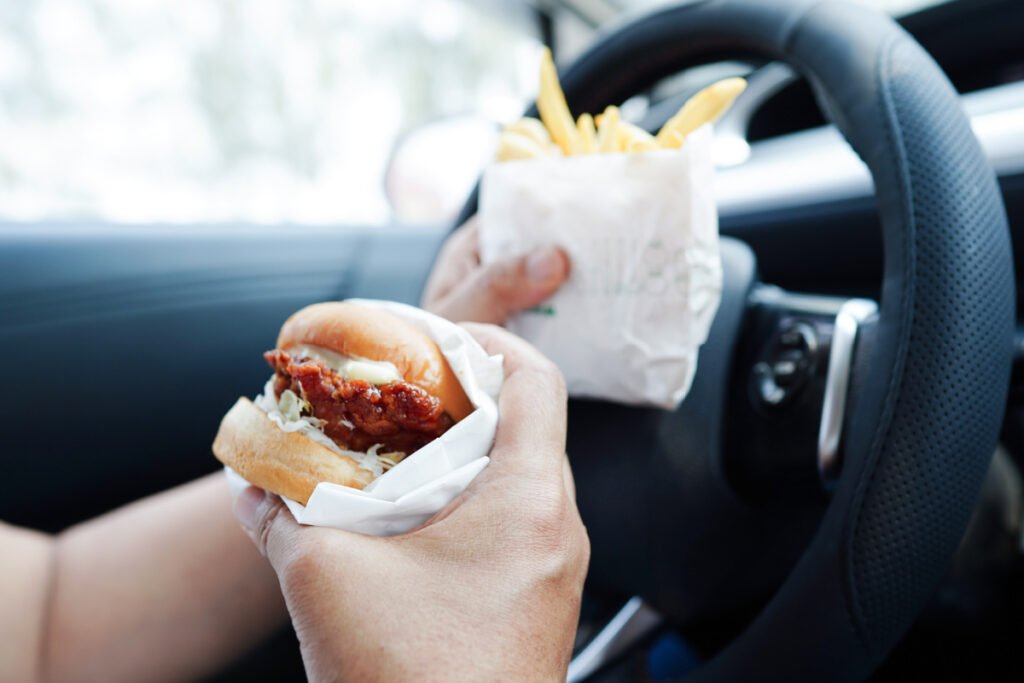 Woman eating fast food burgers and fries in the car