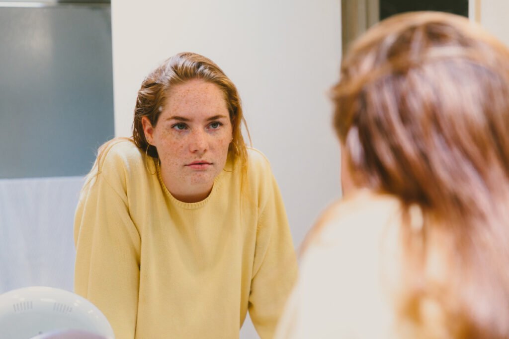 Young woman looking into mirror